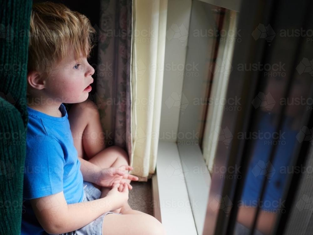 Blonde Boy with Down syndrome Looking Out Window - Australian Stock Image