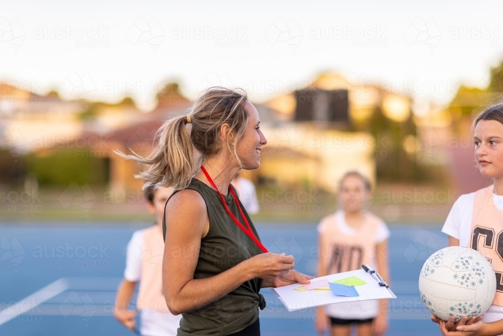 Image of blonde female netball coach with school kids on netball court ...