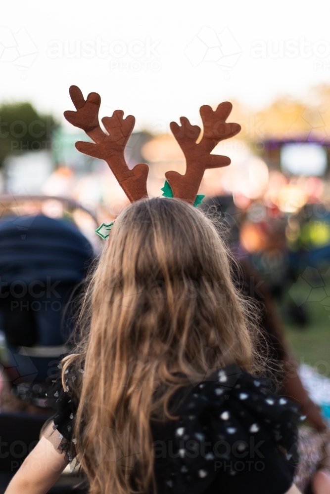 blonde girl wearing antlers watching christmas carols - Australian Stock Image