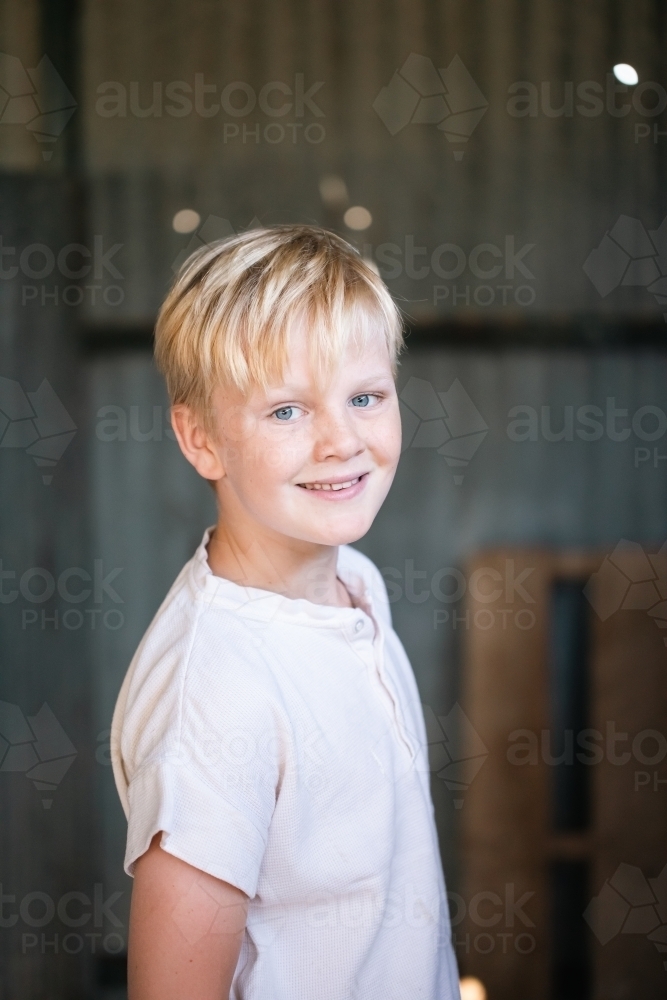 blonde pre-teen boy with relaxed pose in rustic county setting - Australian Stock Image