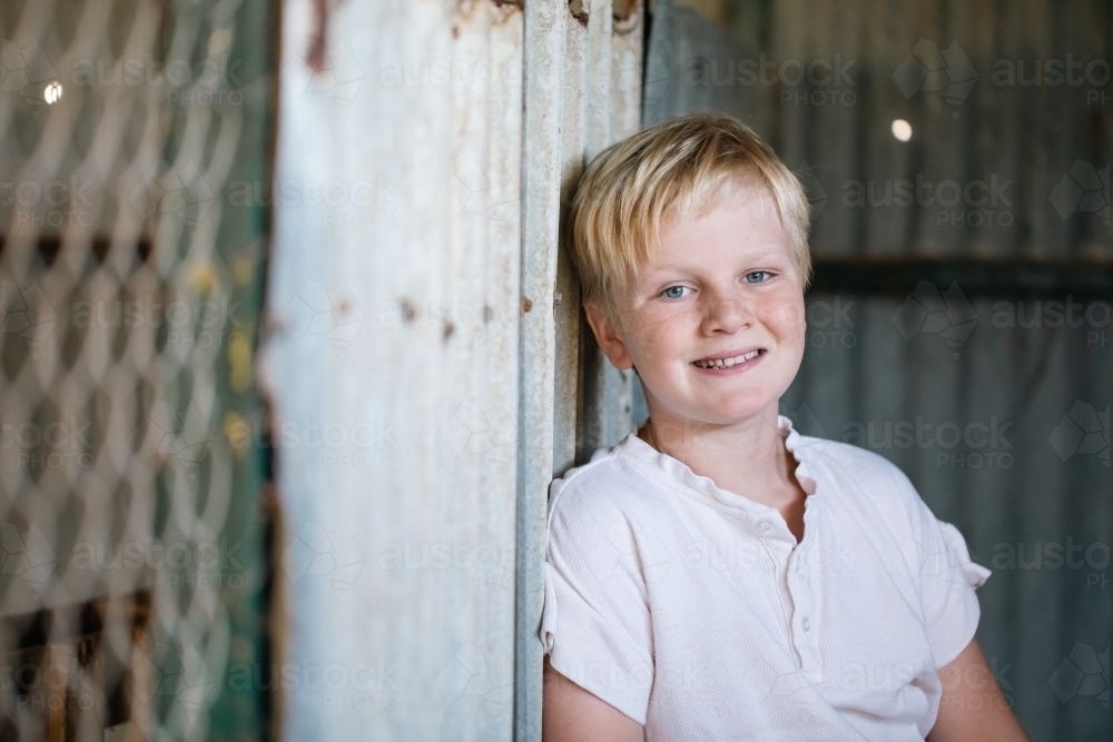 Blonde pre-teen boy with relaxed pose in rustic outdoor county setting - Australian Stock Image