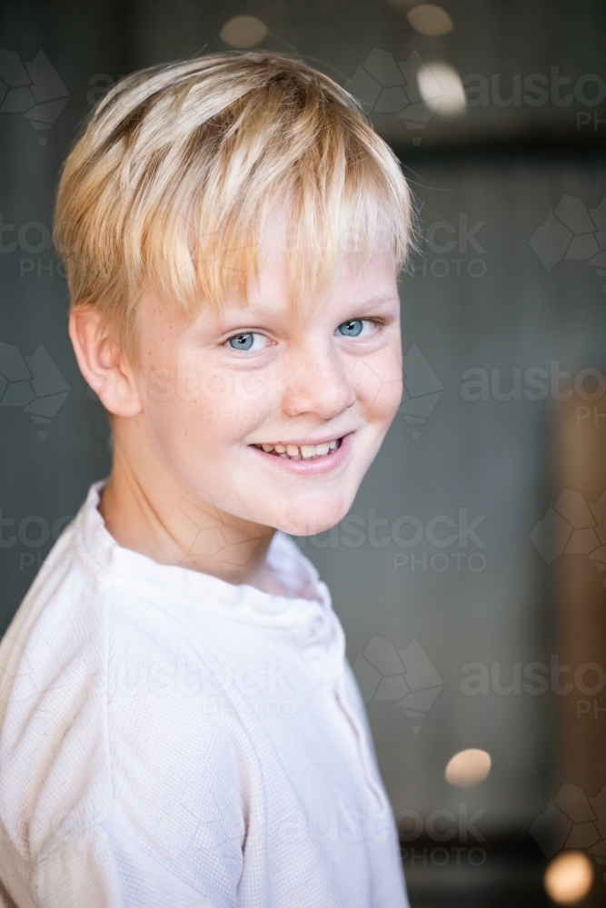 Blonde pre-teen boy with relaxed pose sitting in rustic outdoor county setting - Australian Stock Image