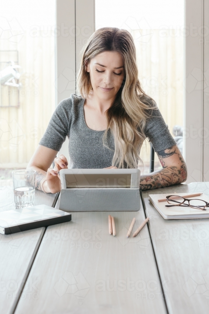 Blonde young woman working on a tablet at home - Australian Stock Image