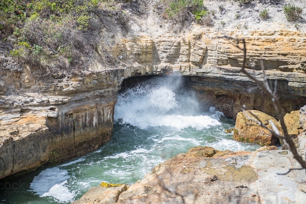 Blowhole and waves in coastal rocks - Australian Stock Image