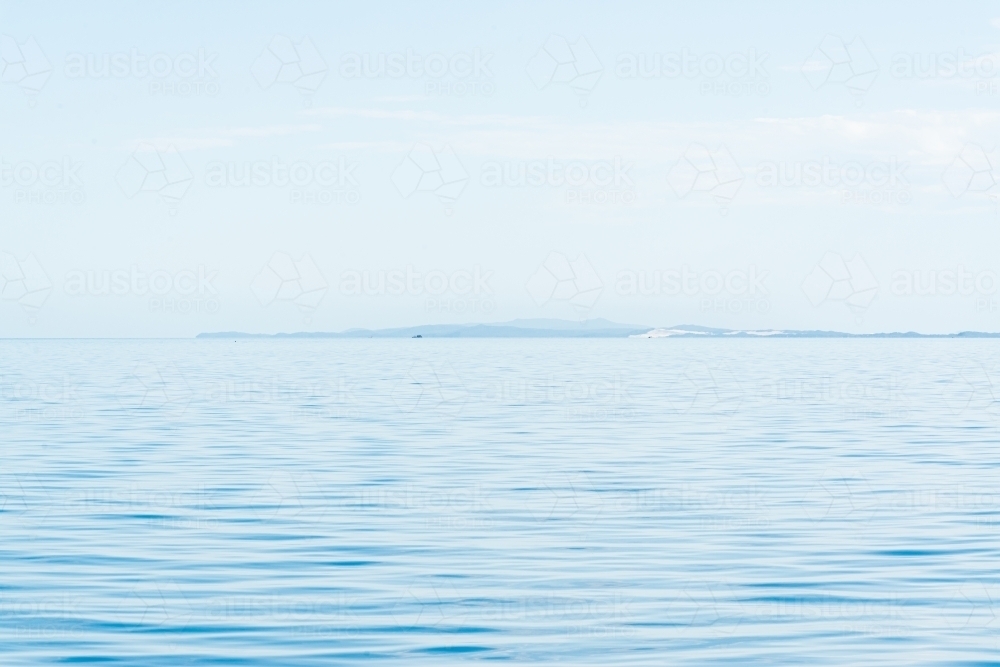 Blue and blue sky with hazy islands on horizon - Australian Stock Image
