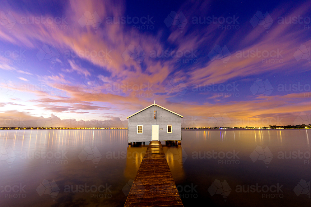 Blue boathouse at twilight on a calm reflective river. - Australian Stock Image