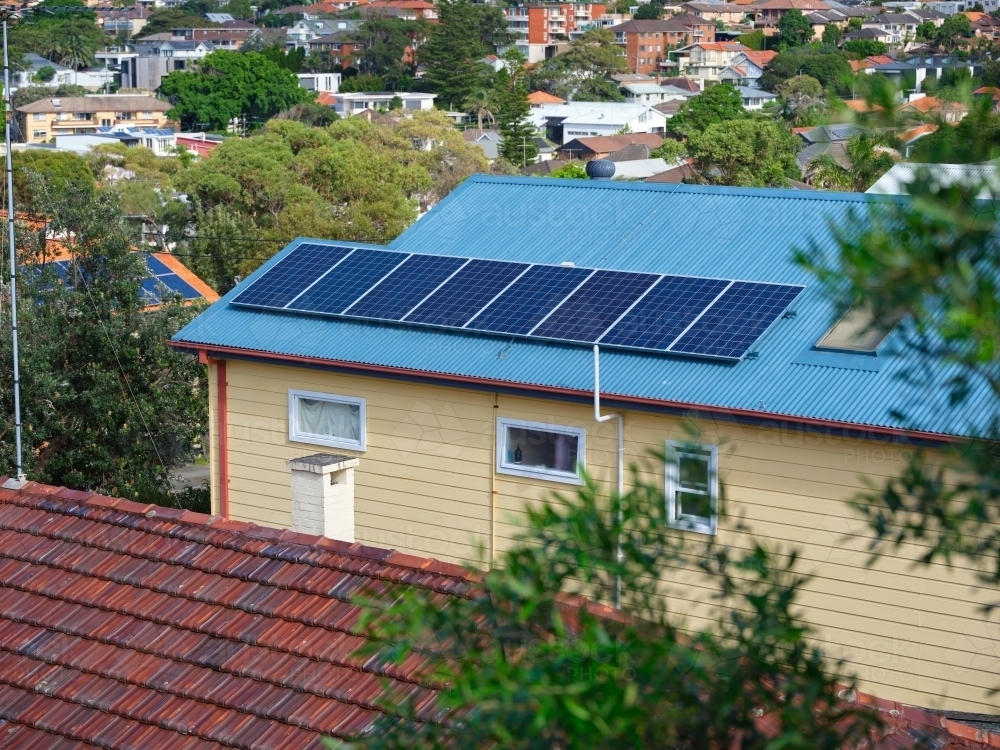 Blue colored roof with solar panels and a view with houses - Australian Stock Image