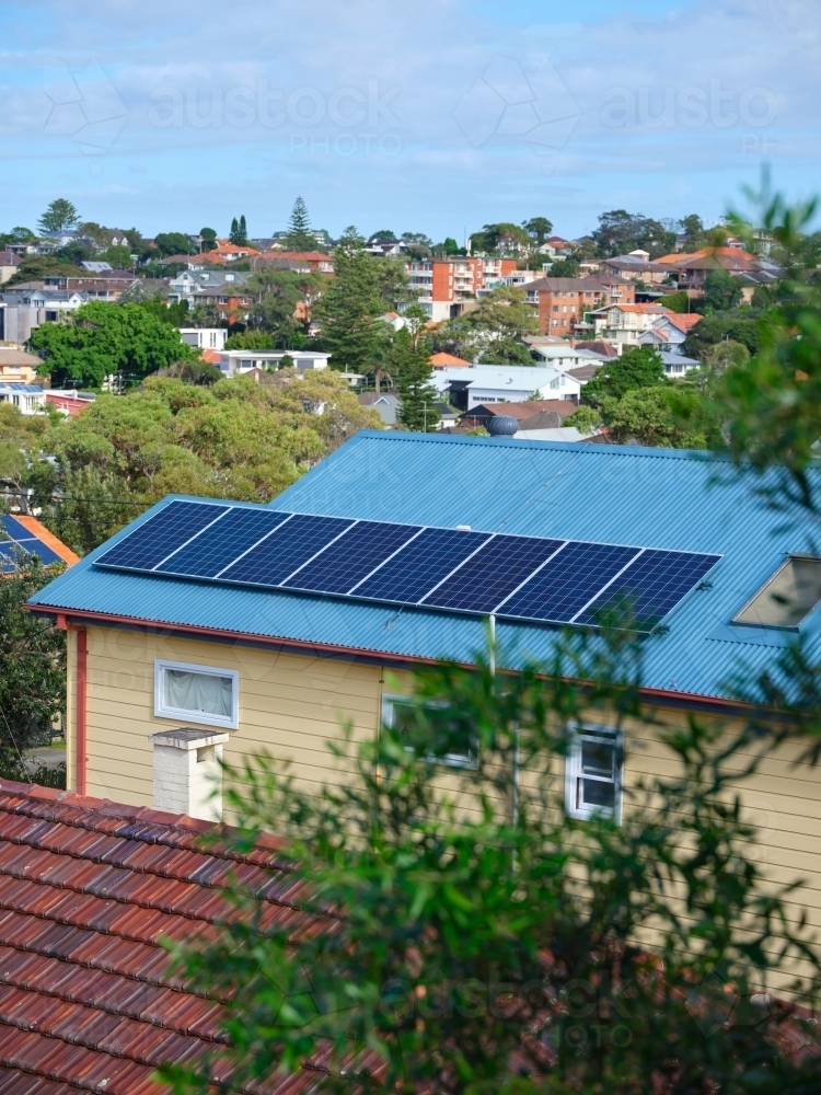 Image of Blue coloured roof with solar panels and a view with houses ...