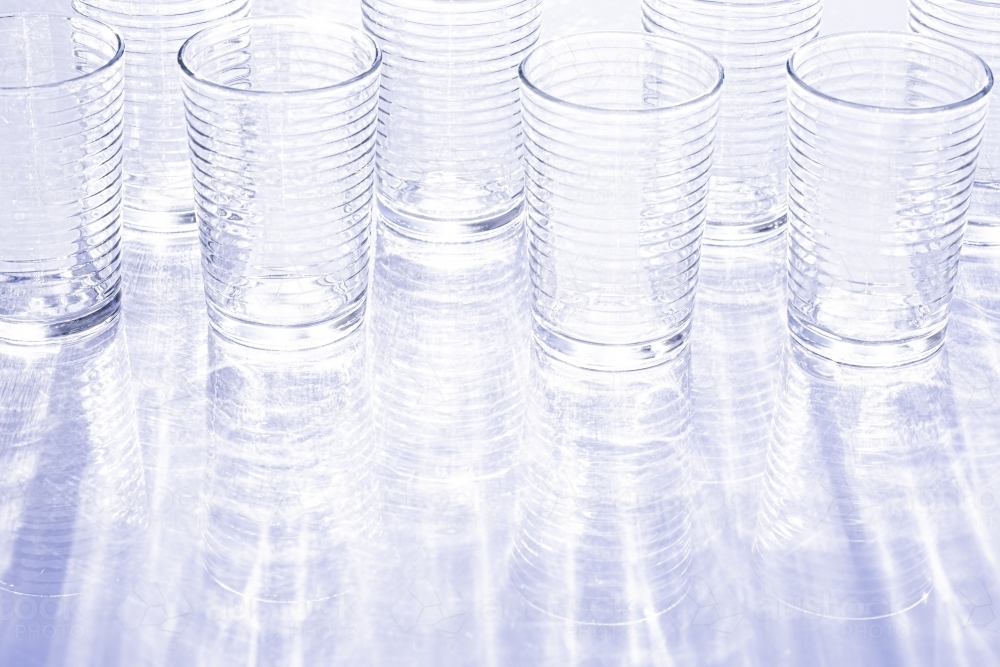 Blue - purple glasses reflecting light with reflected rippled shadow pattern - Australian Stock Image
