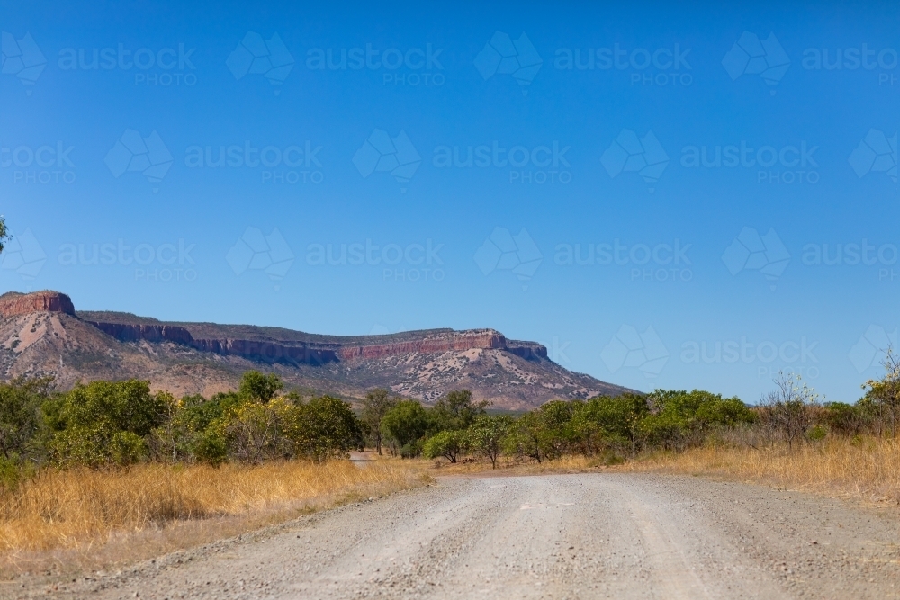 blue sky above an unsealed Gibb River Road with Cockburn Range in the distance - Australian Stock Image