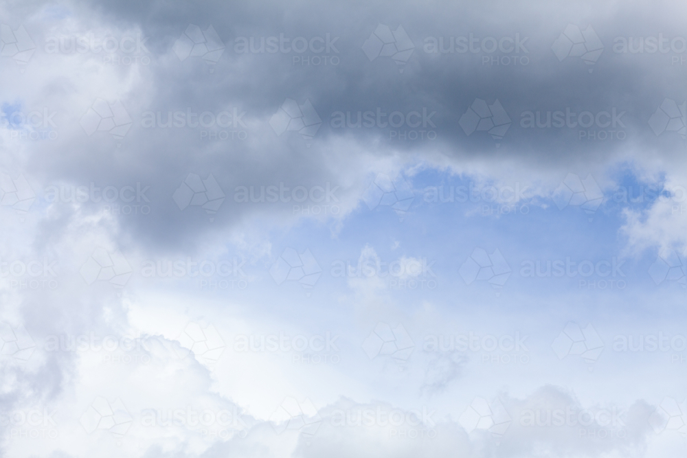Blue spot of sky appearing through cloudy grey sky after rain - Australian Stock Image