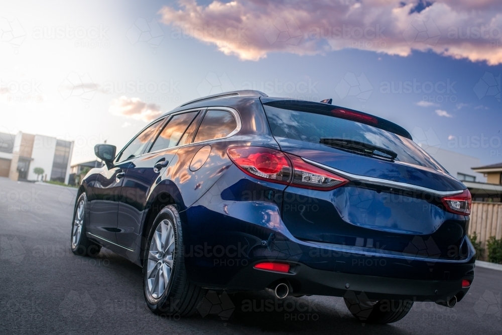 Blue station wagon on suburban street with luxury homes - Australian Stock Image
