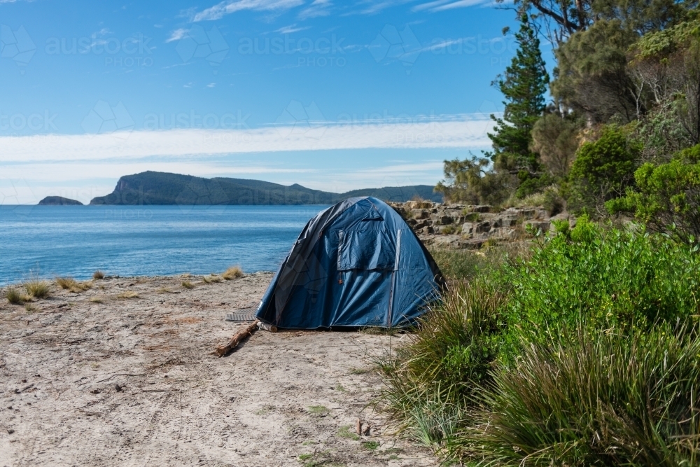 blue tent in a remote location by the sea - Australian Stock Image
