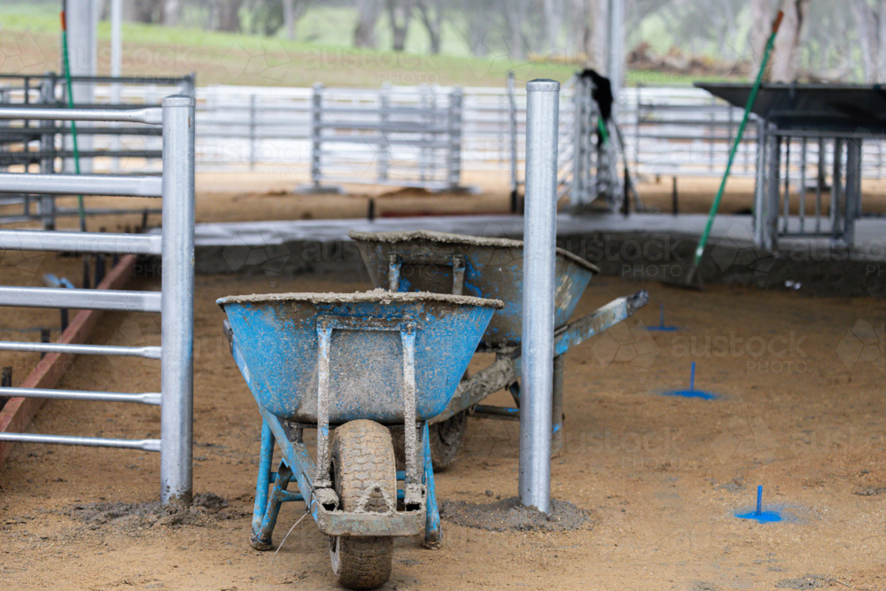 Blue wheelbarrow carrying concrete on a construction site - Australian Stock Image