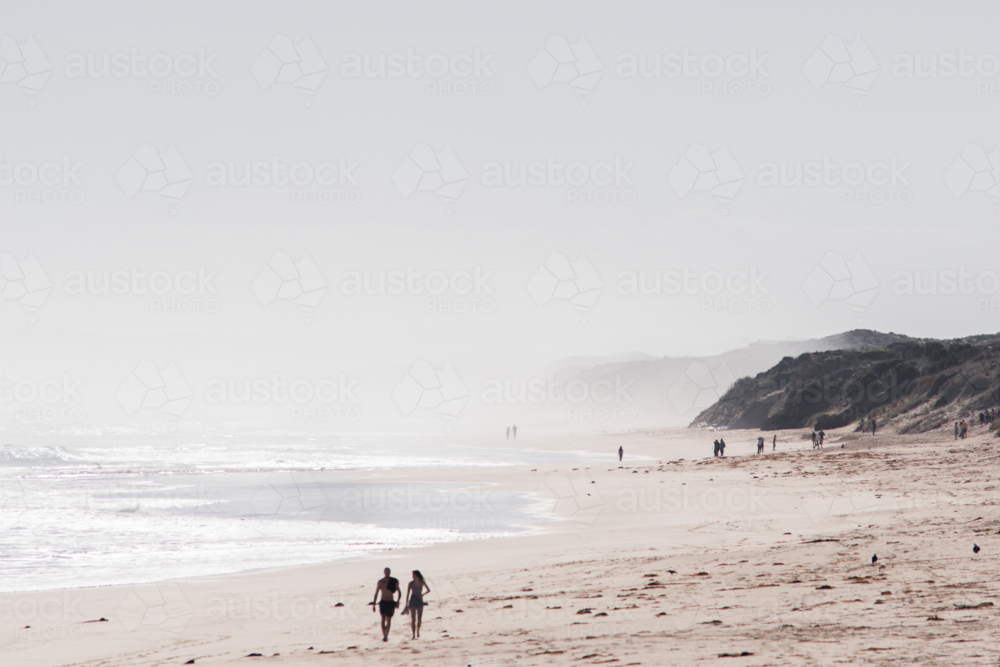 blurred couple walking on hazy beach on summers day - Australian Stock Image