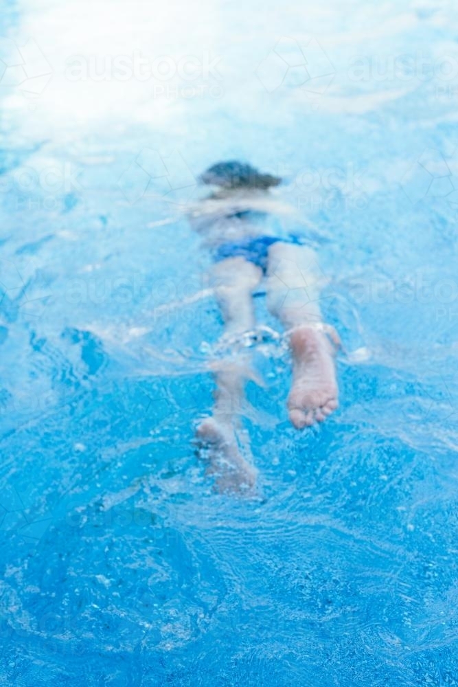 blurred image of a girl swimming in a pool - Australian Stock Image