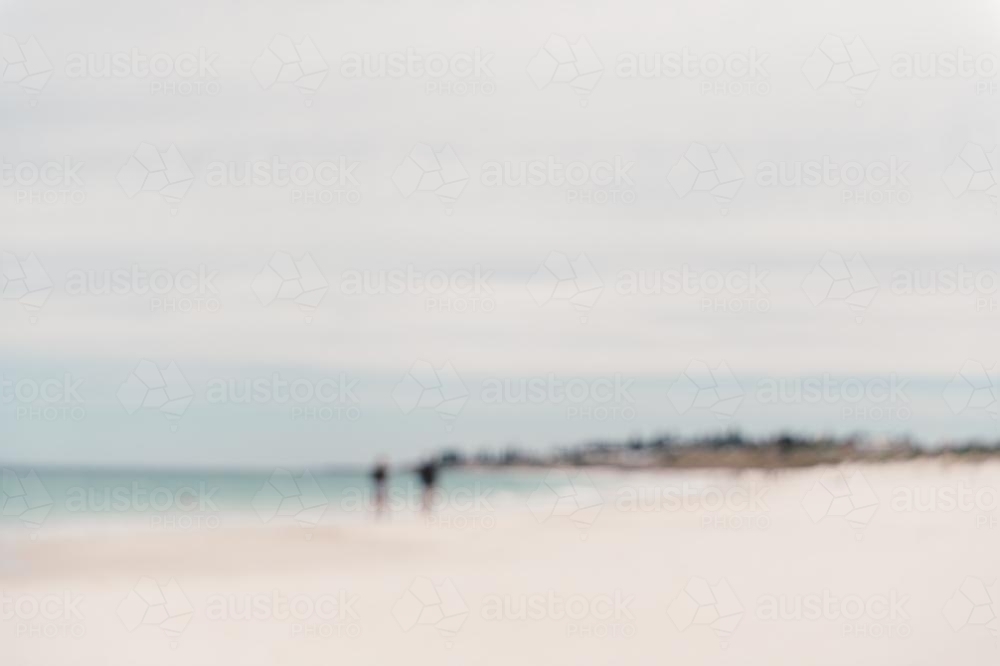 Blurred image of two people walking on a beach in summer - Australian Stock Image