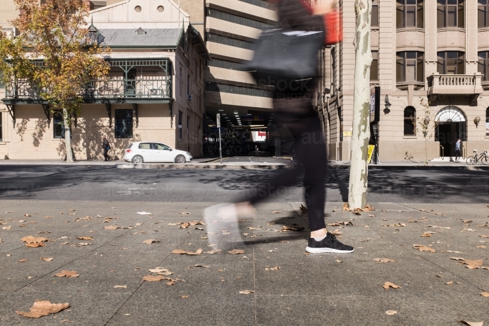 blurred motion of person walking by on a city footpath - Australian Stock Image