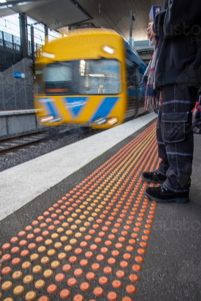 blurred Person standing on a train platform with a train arriving - Australian Stock Image
