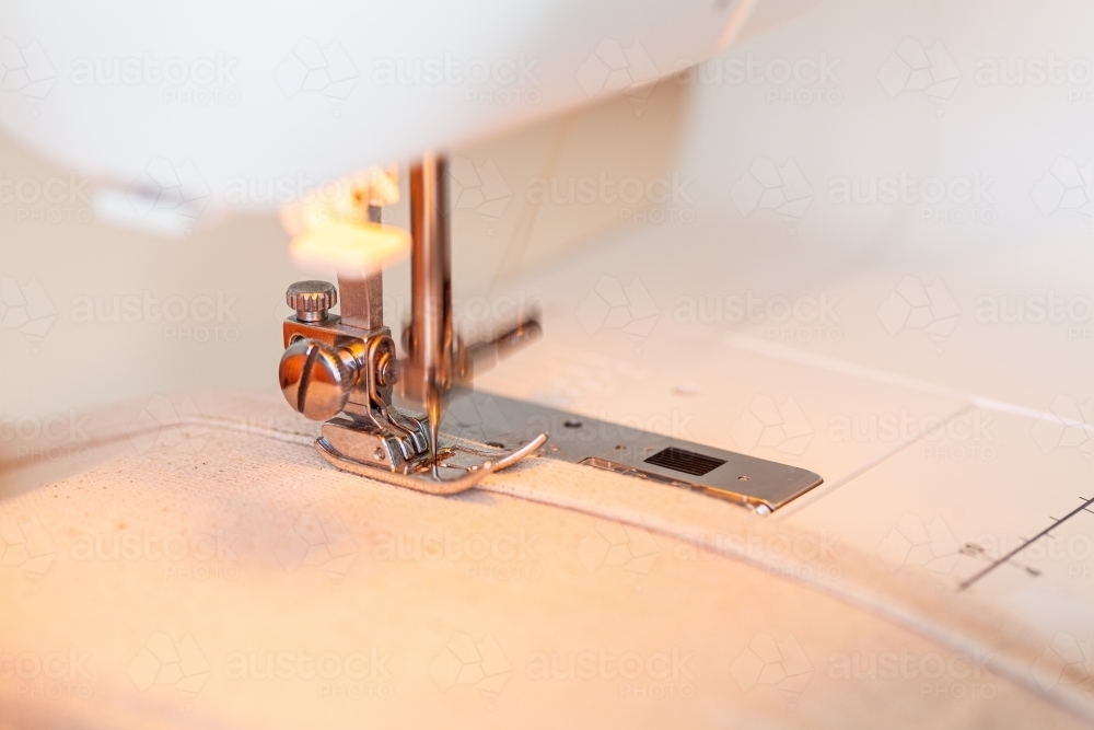 Blurred sewing machine needle going into canvas fabric - Australian Stock Image