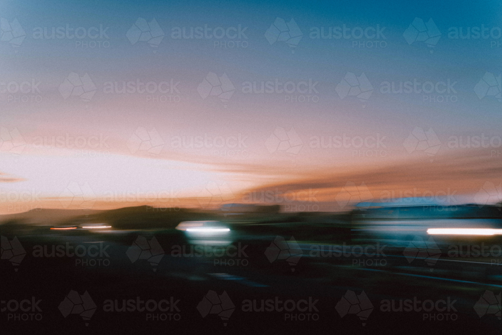 Blurred sunset road with moving cars flashing lights - Australian Stock Image