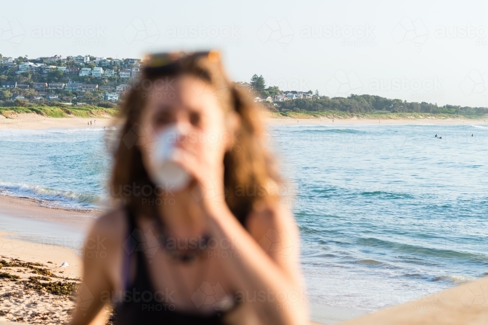 blurred woman, at beach in the morning with coffee - Australian Stock Image