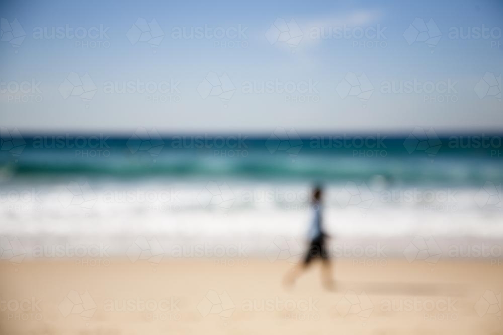 Blurry image of a woman walking along the beach - Australian Stock Image