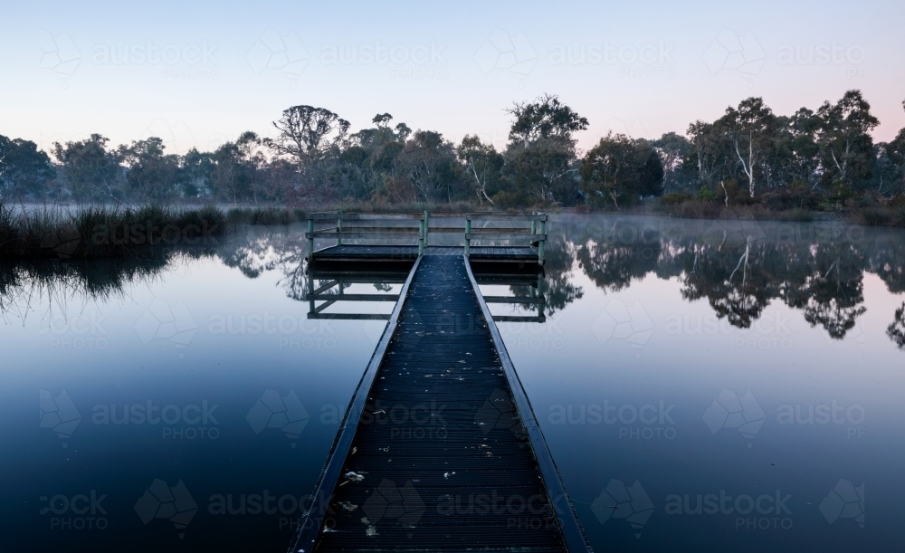 boardwalk over still water on cold morning - Australian Stock Image
