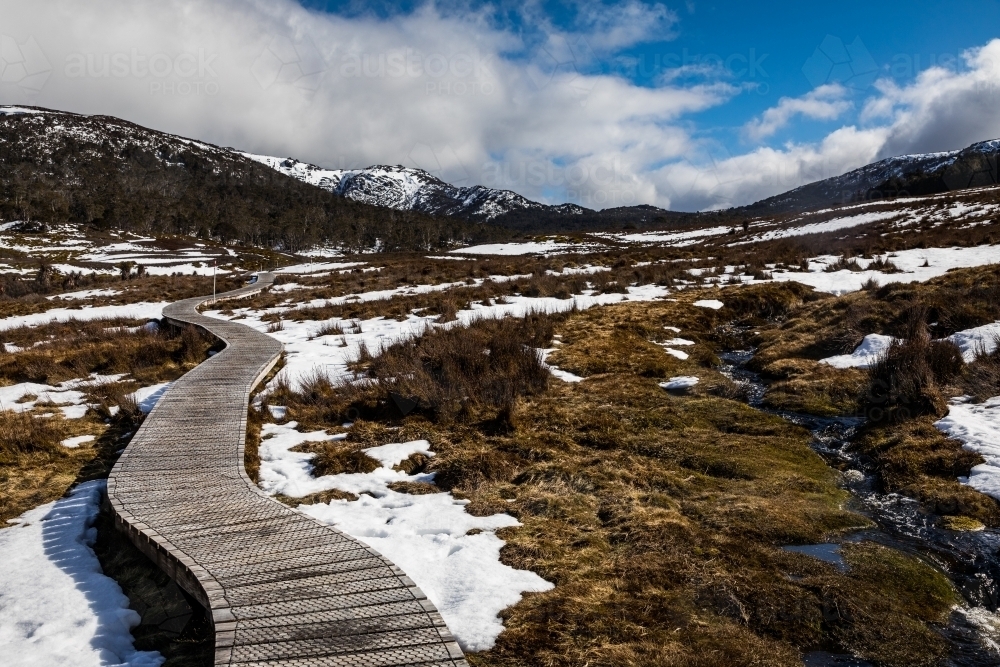 Boardwalk through mountainous area with melting snow - Australian Stock Image