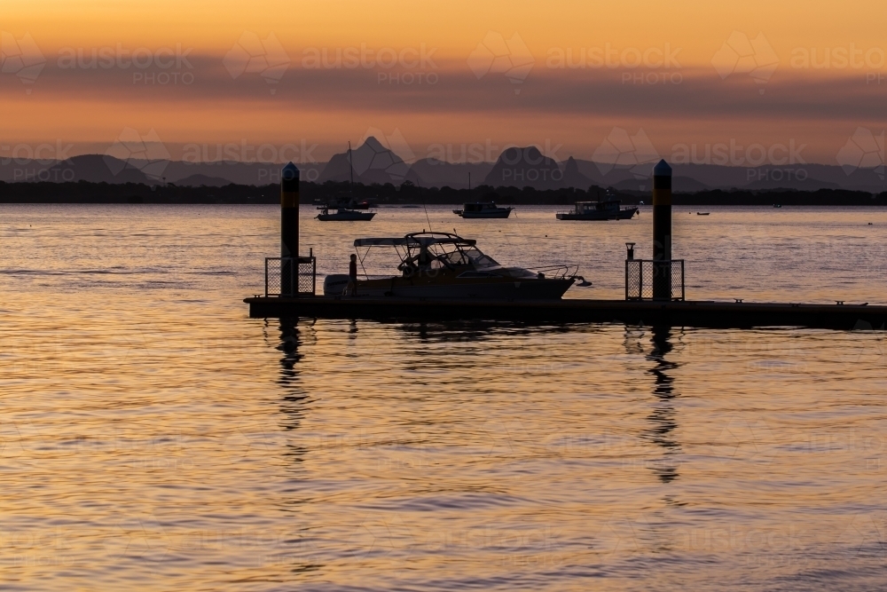 Boat and dock silhouetted in Pumicestone Passage - Australian Stock Image