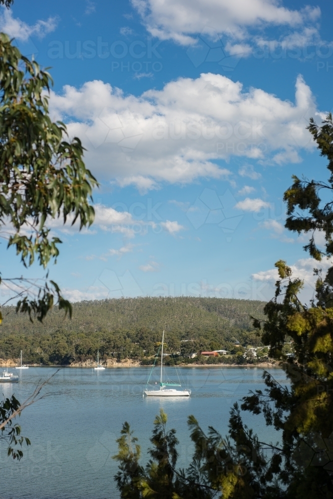 Boat in calm water surrounded by trees and hills - Australian Stock Image