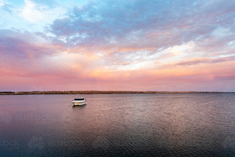 boat moored in calm bay at sunrise - Australian Stock Image
