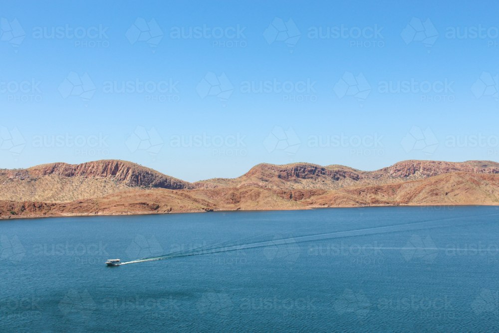 Boat sailing across lake with mountain views - Australian Stock Image