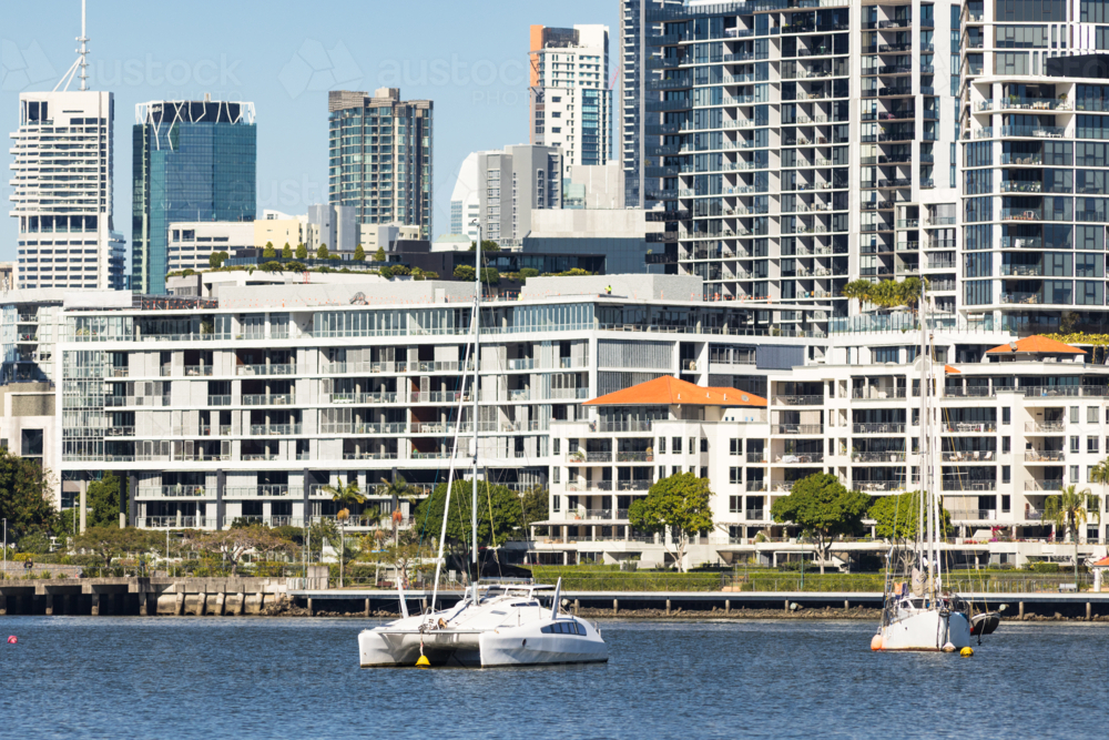 Boats on the Brisbane River with riverfront apartment blocks lining the river in Newstead - Australian Stock Image