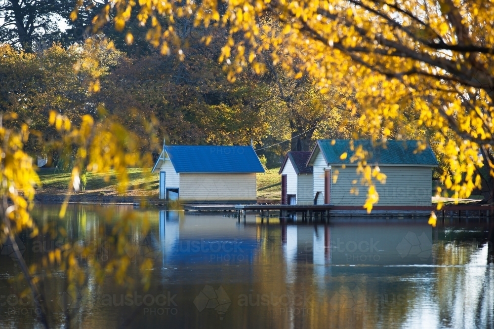 Boatsheds on a lake in Autumn - Australian Stock Image