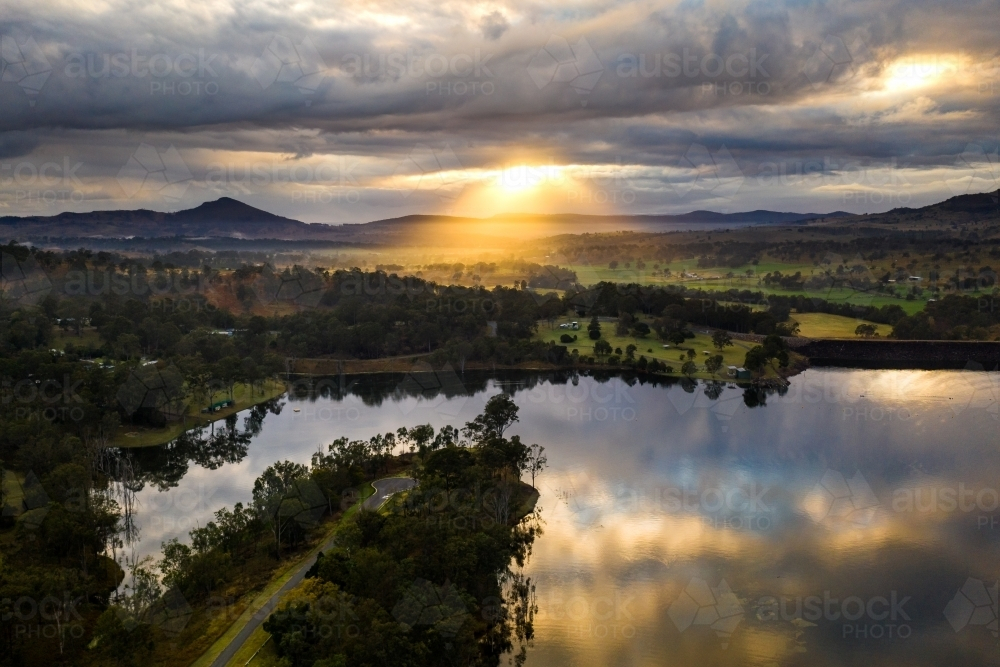 Body of calm water mirrors the cloudy sky in sunset landscape - Australian Stock Image