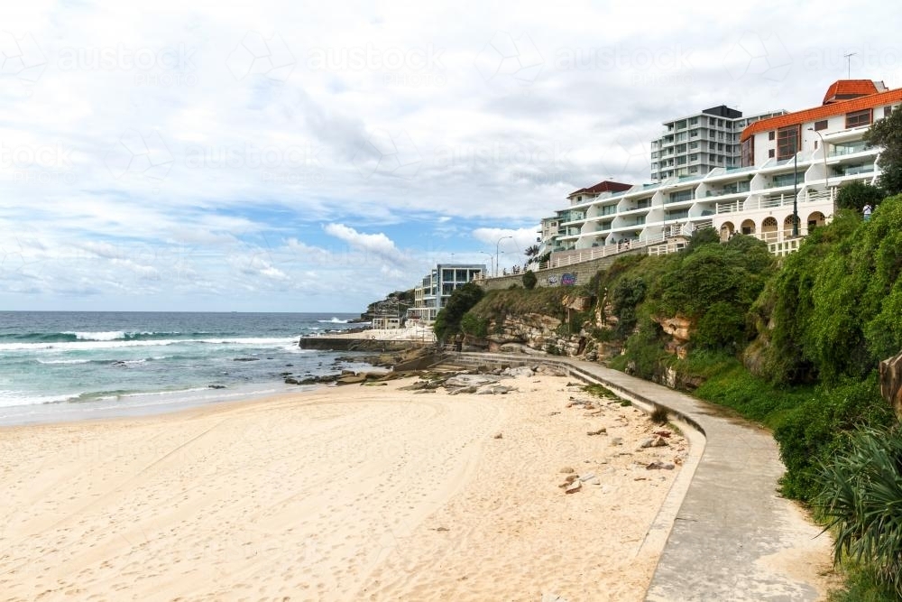 Bondi Beach walking path looking towards Bondi Baths and luxury beachfront properties - Australian Stock Image