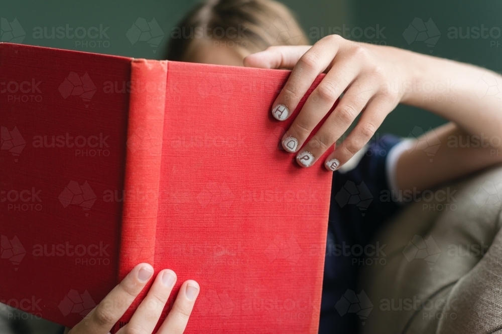 Book in child's hand with "hope" written on the nails - Australian Stock Image