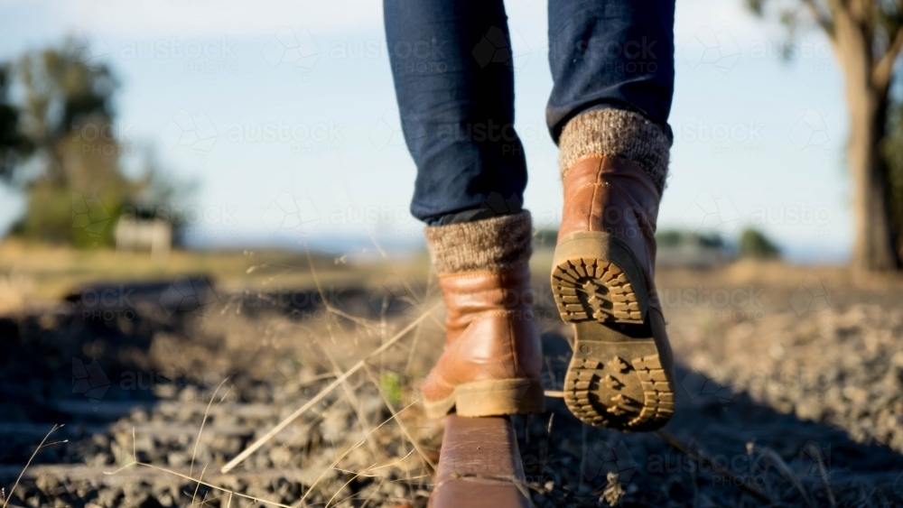Image of Booted feet walking away on railway tracks - Austockphoto