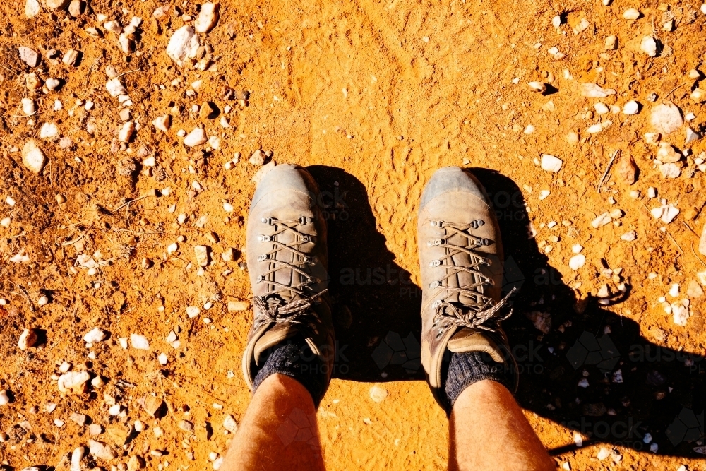 Boots and legs on a red earth trail in Central Australia. - Australian Stock Image