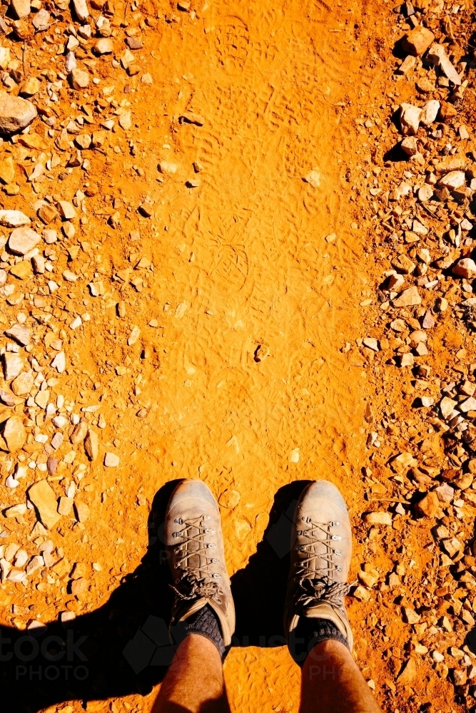 Boots and legs on a red earth trail in Central Australia. - Australian Stock Image