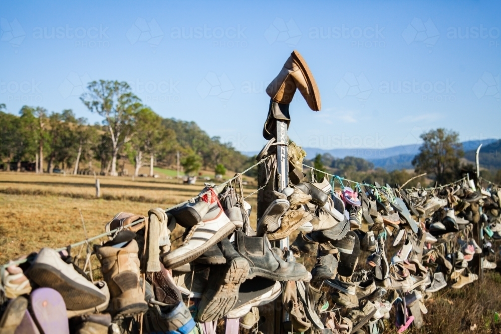Boots and shoes hanging on fence on boot hill - Australian Stock Image