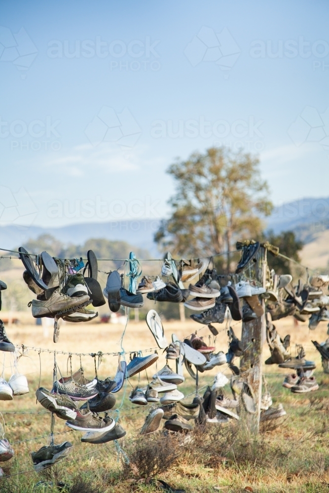 Boots and shoes hanging on fence on boot hill - Australian Stock Image