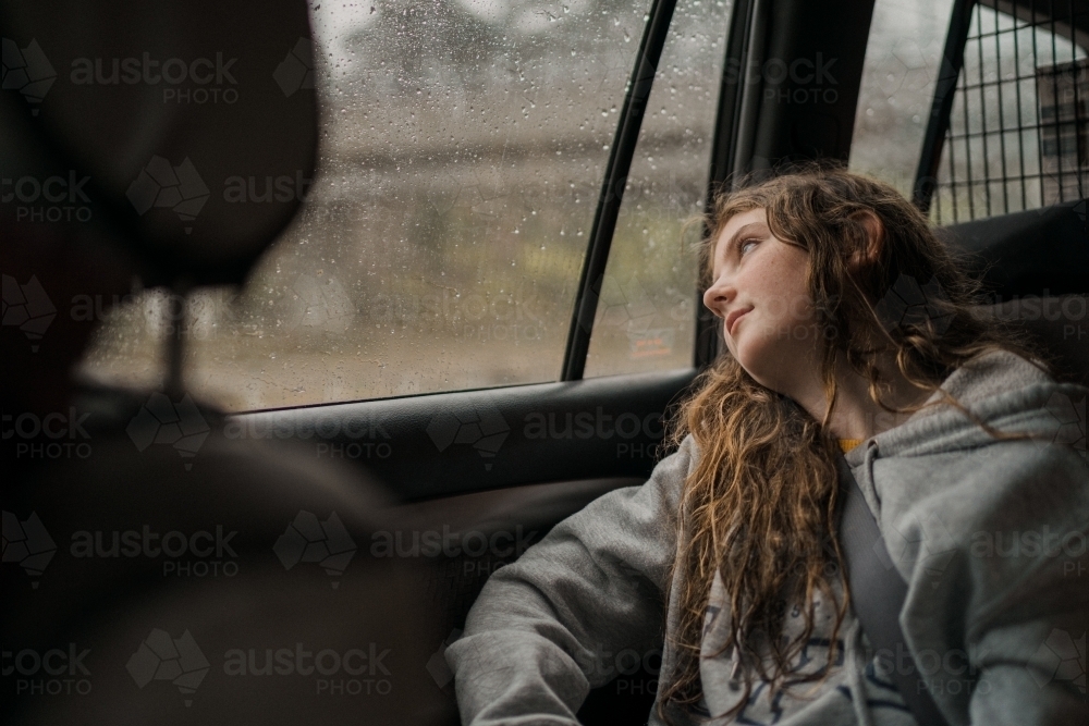 bored girl in car during long rainy trip - Australian Stock Image