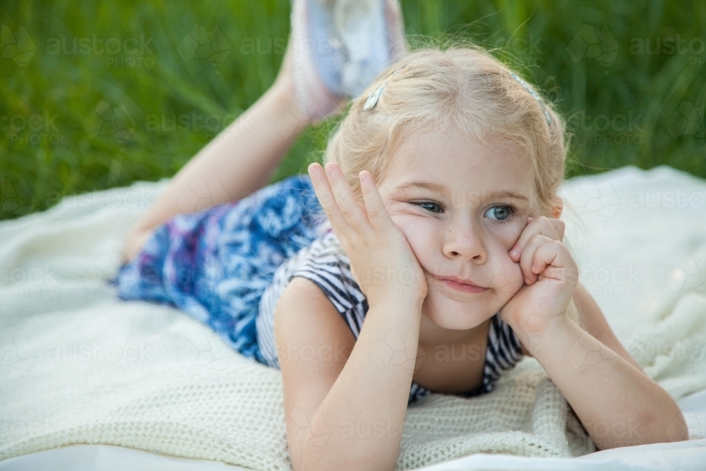 Bored little girl resting face in hands outside - Australian Stock Image