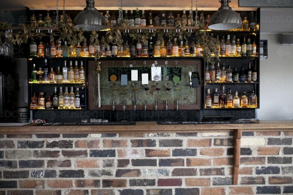 Bottles and beer taps behind bar at craft beer pub - Australian Stock Image