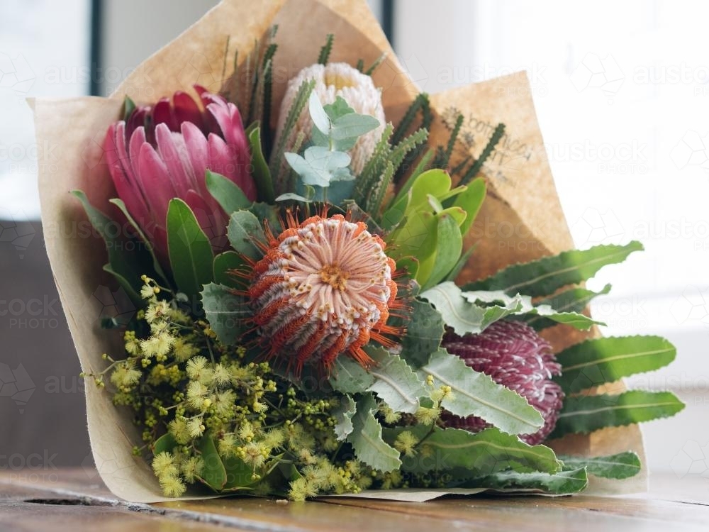 Bouquet of native flowers wrapped in brown paper on a table - Australian Stock Image