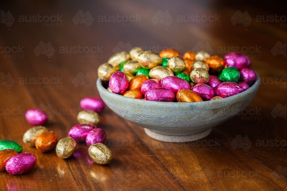 Bowl of colourful chocolate Easter eggs on wood - Australian Stock Image