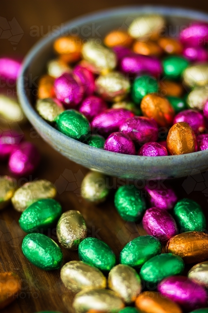Bowl of colourful chocolate Easter eggs on wood - Australian Stock Image