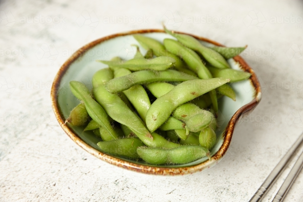bowl of edamame with metal chopsticks on the side - Australian Stock Image
